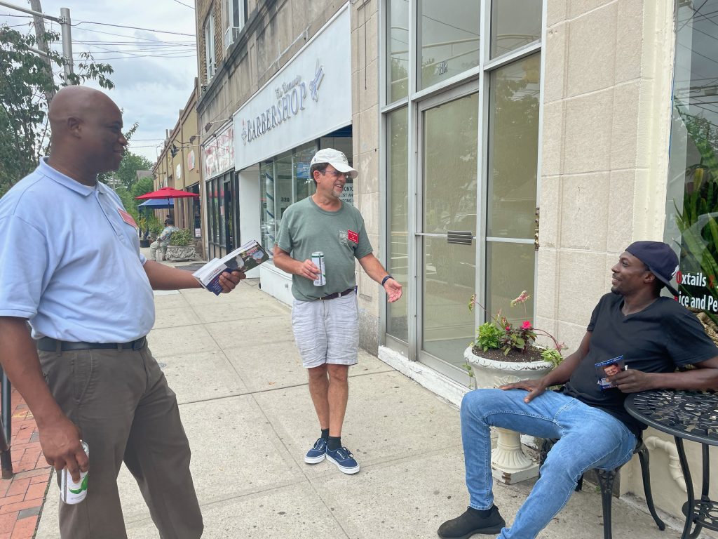 Tafari Anderson speaking with residents outside a neighborhood business.