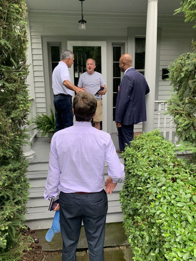 Campaign volunteers speaking with a resident at a front door.