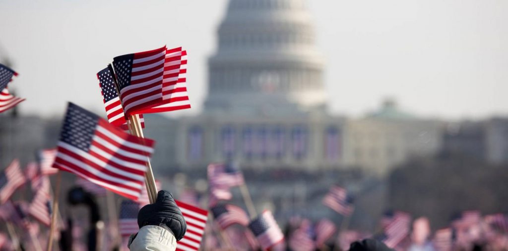 American flags in front of the United States Capitol during a public gathering.